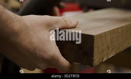 Carpenter's hand firmly holds a solid wood board, ready for crafting Stock Photo