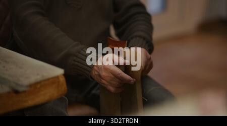 Hands manipulate tan leather with care in a focused workshop setting Stock Photo