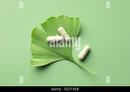 Ginkgo biloba leaf and pills on green background, flat lay Stock Photo