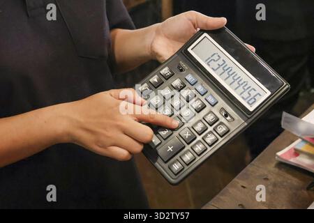 Close up of focused person holding calculator, finger pressing button for business finance and accounting. Math calculation with large number on displ Stock Photo