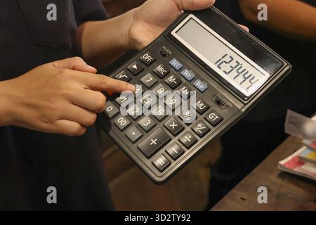 Close up of hand using black calculator for business accounting and finance. person carefully pressing number on keyboard for budget calculation Stock Photo