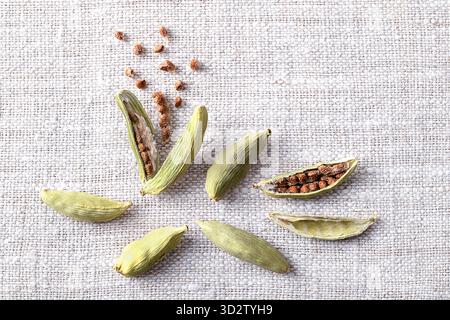Dried cardamom pods with seeds, close-up, on linen. Light green fruits of Elettaria cardamomum, spindle shaped seed pods with small seeds. Stock Photo