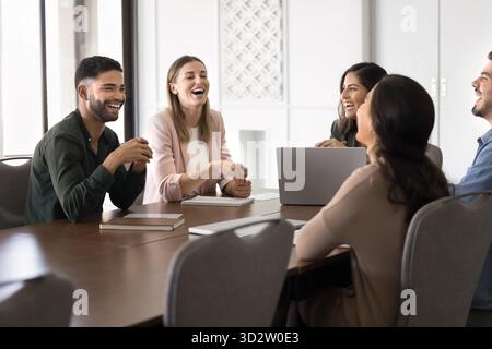 Diverse coworkers laughing together during team meeting Stock Photo