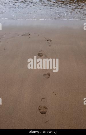 Footprints in the sand, the edge of the sea. Stock Photo