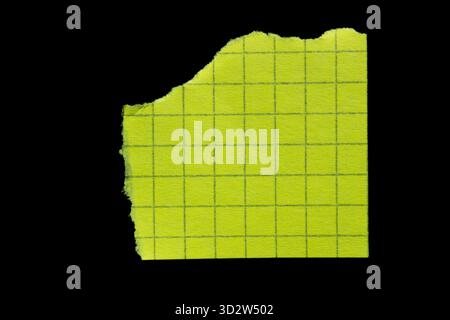 Ripped yellow grid note paper torn edges isolated on black background Stock Photo