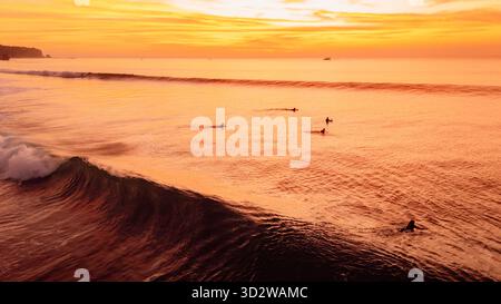 Golden sunset over ocean waves with surfers and bright sky Stock Photo