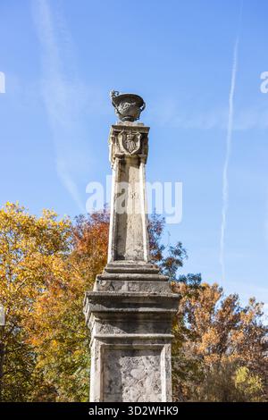 A low-angle view of an old stone column monument topped with an urn, featuring the year 1859, against a clear blue sky in Topčiderski Park, Belgrade. Stock Photo