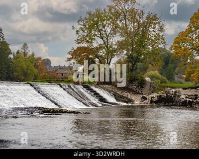 Weir at Linton Hydro on the River Wharfe near Grassington, with autumn colours in the surrounding countryside. Stock Photo