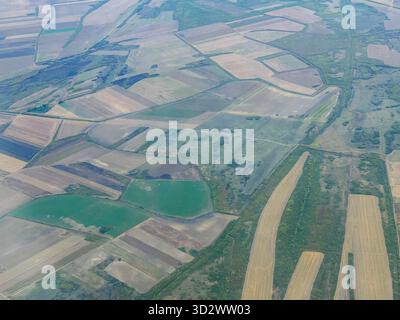 Aerial perspective of agricultural land arranged in geometric patterns, with different field colors and boundaries. Stock Photo