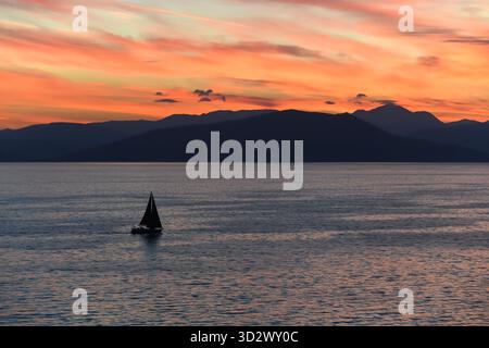 A yacht sails in the calm Ionian Sea at sunset. Stock Photo