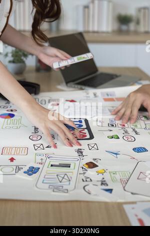 Close-up of designers' hands working on user interface sketches and digital concepts, emphasizing collaboration and creativity Stock Photo