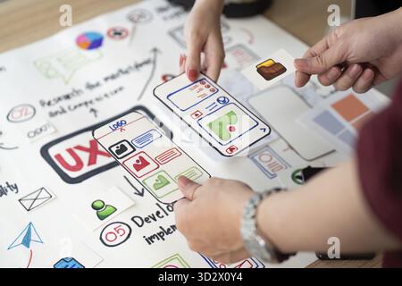 Hands-on collaboration in UX design, focusing on user interface elements and app features with visual aids Stock Photo