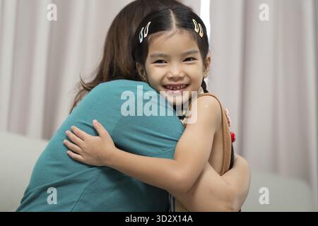 A joyful moment captures a mother hugging her daughter, radiating affection and love in a cozy indoor setting Stock Photo