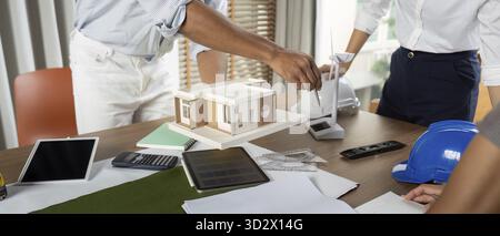 Engineers working at their workstation, skillfully finalizing innovative project designs using high-tech tools and models focused on sustainability Stock Photo