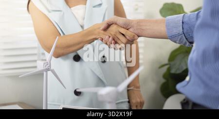 A handshake between two colleagues symbolizes a partnership for sustainability in their workplace, emphasizing collaboration and commitment Stock Photo