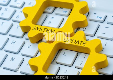 Two interlocking gear with text SYSTEM UPDATE on a computer keyboard. Improvement, maintenance, or software upgrade concept. Stock Photo