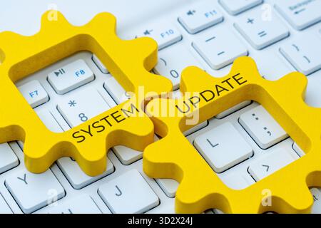 Two interlocking gear with text SYSTEM UPDATE on a computer keyboard. Improvement, maintenance, or software upgrade concept. Stock Photo