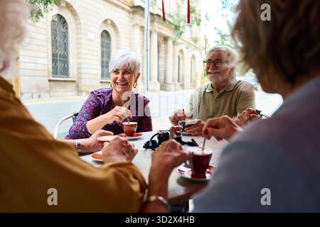 Senior friends enjoying coffee and conversation at outdoor cafe Stock Photo