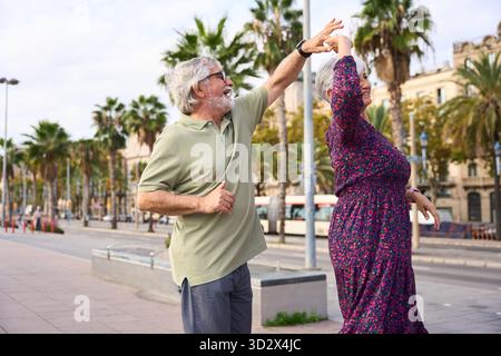 Senior couple dancing with joy in city street Stock Photo