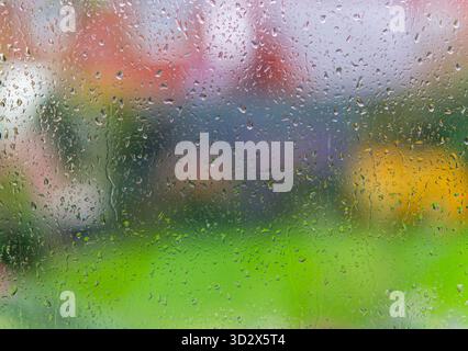 A view of a suburban back garden seen through a window covered in raindrops Stock Photo