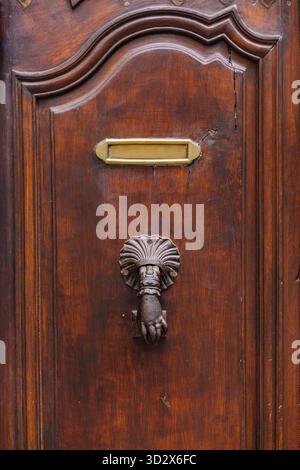 Vintage iron door knocker in the shape of a hand on an old wooden door Stock Photo