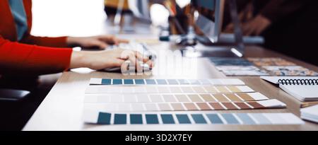 A vibrant creative workspace showcasing color palettes arranged neatly on a desk, featuring computer screens and design tools, ideal for artistic coll Stock Photo