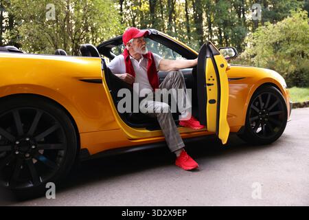 Stylish senior man getting out of modern cabriolet outdoors Stock Photo
