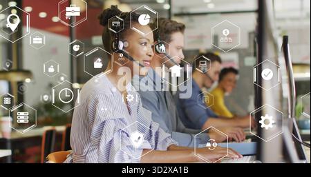 Typing call center rep with headset in office, with monitors, keyboard, hexagonal icons, copy space Stock Photo