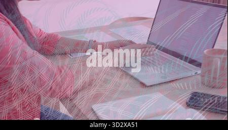 Asian Indian woman in pink top with colleague typing on silver laptop at home, copy space Stock Photo