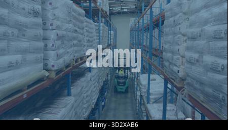 Operating green forklift, warehouse worker wearing safety gear carrying pallets in warehouse aisle Stock Photo