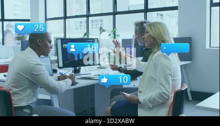 Analyzing charts, three business professionals collaborating around desk in office with monitors Stock Photo