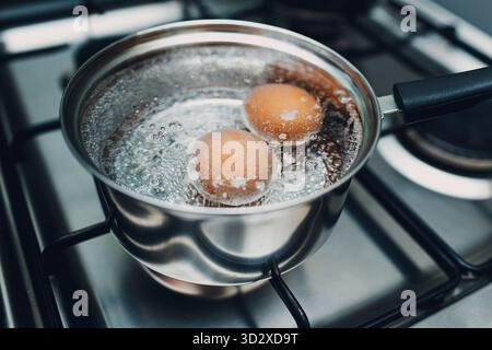 Saucepan stainless steel with boiling eggs breakfast in water on gas stove Stock Photo
