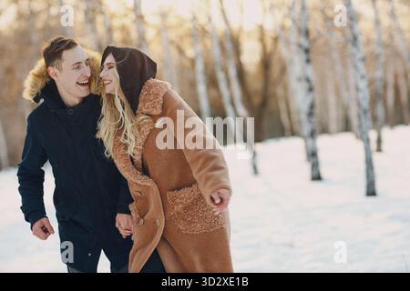 Loving young couple man and young woman walking and having fun in winter forest park Stock Photo