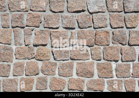 Texture of masonry of red granite, natural stone and concrete rows Stock Photo