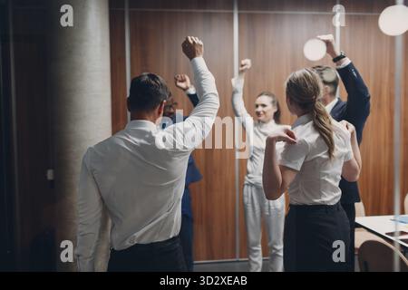 Businessman and businesswoman team doing warming up exercises before office meeting. Business healthy successful people group man and woman after conf Stock Photo