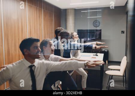 Businessman and businesswoman team doing warm-up and yoga exercises before office meeting. Business healthy successful people group man and woman afte Stock Photo