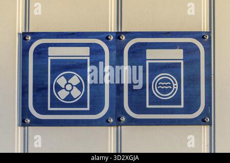 Signs showing illustration of washing machine and dryer, white and blue signs on white plank wall Stock Photo
