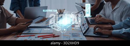 A modern workspace showcasing collaborative efforts on electric car technology, featuring digital devices, data analysis, and eco-friendly innovations Stock Photo