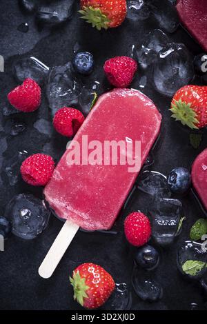 Refreshing popsicle on ice cubes and fruits, food background Stock Photo