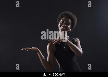 Empty female hand of african american woman holding and pointing on black background Stock Photo