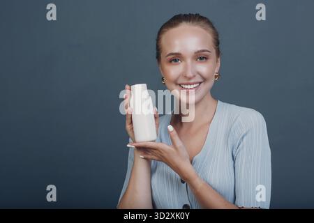 Pretty young european woman hold white bottle template blank empty space. Shampoo or cosmetics Stock Photo