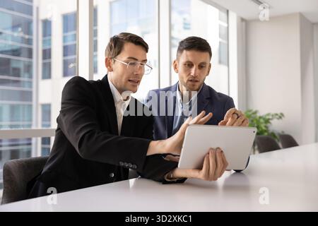Two busy male professional colleagues working together with digital tablet Stock Photo