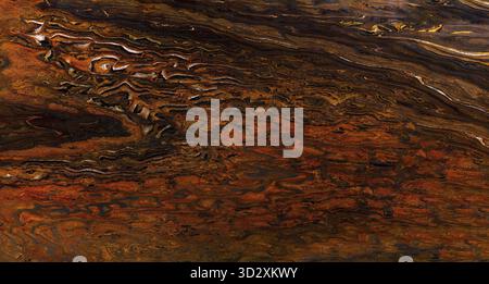 Natural granite stone texture featuring rich orange, brown, and black swirling patterns Stock Photo