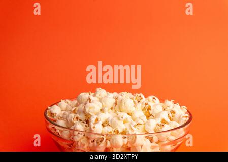 Close-up of popcorn in a glass bowl on orange background, showing texture, detail, and food concept ideal for commercial and creative use Stock Photo