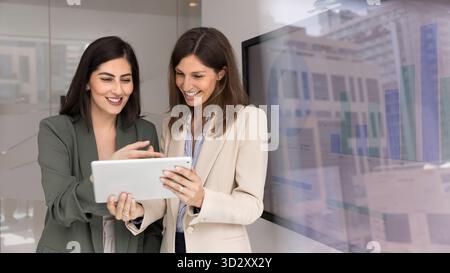 Two happy business women using tablet for sharing advice Stock Photo