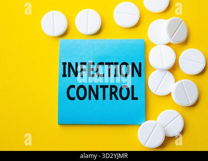 Infection Control symbol. Concept word Infection Control on blue note. Beautiful yellow background with pills. Medicine and Infection Control concept. Stock Photo