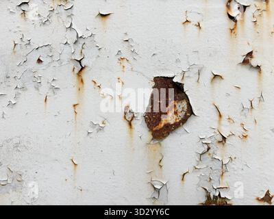Red spots of peeling white paint on rusty metal. Traces of age on metal. Abstract background Stock Photo
