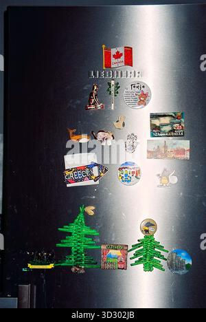 Magnets on silver refrigerator doors, including one with the Canadian flag, captured in analog film with flash lighting. Stock Photo