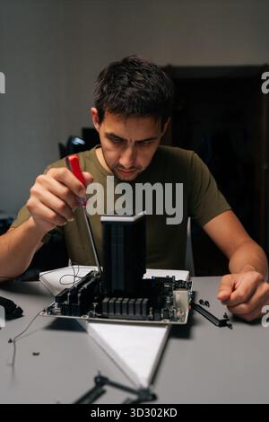 Vertical portrait of technician male installing CPU cooler onto motherboard with screwdriver, conducting maintenance and upgrades on desktop computer Stock Photo