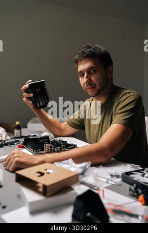 Vertical portrait of repairman mounting CPU cooler on motherboard, performing precise hardware maintenance inside specialized computer repair Stock Photo